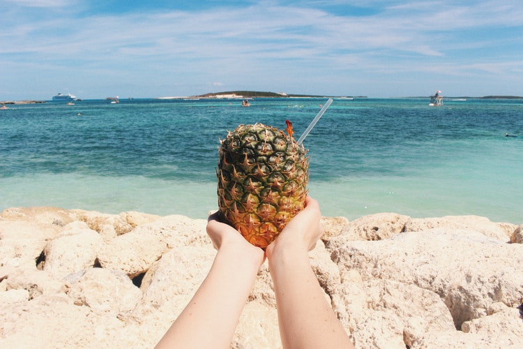 Person holding a pineapple on a beach in Bahamas