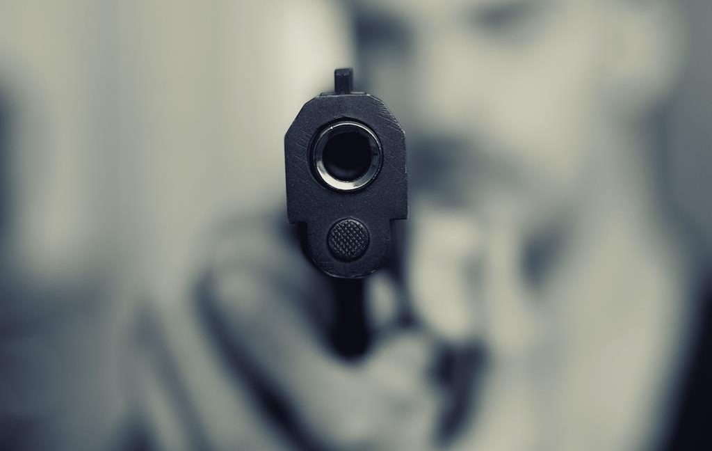 Image of a man pointing a gun directly at the viewer