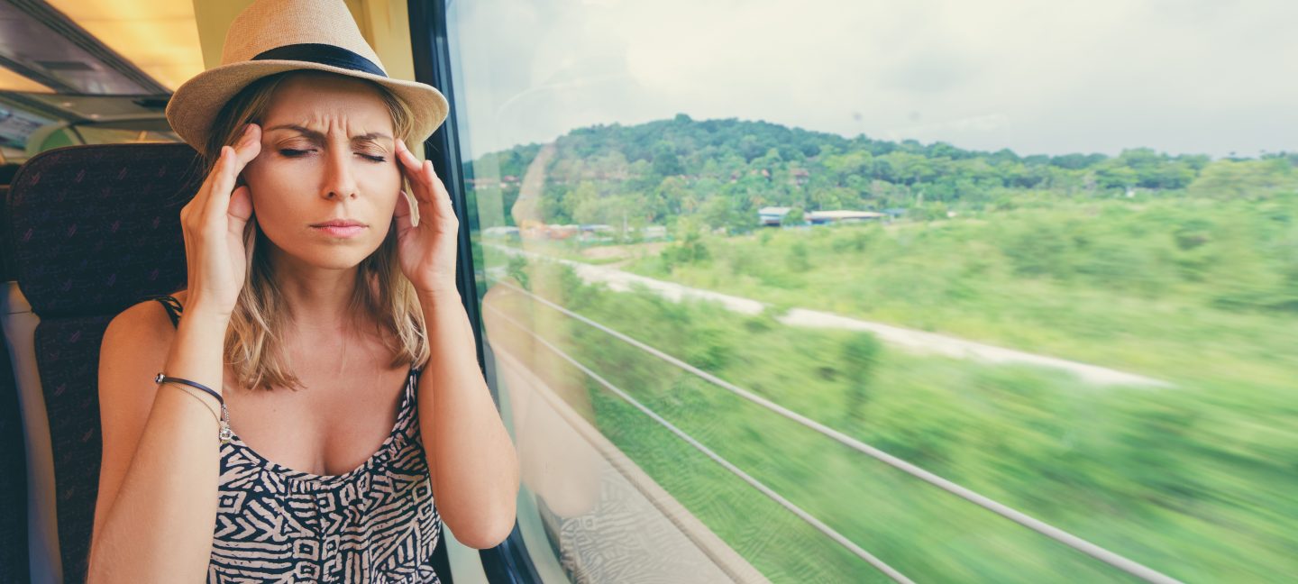 Headache and motion sickness. Stressed and tired young woman sitting near the window while travelling by train.