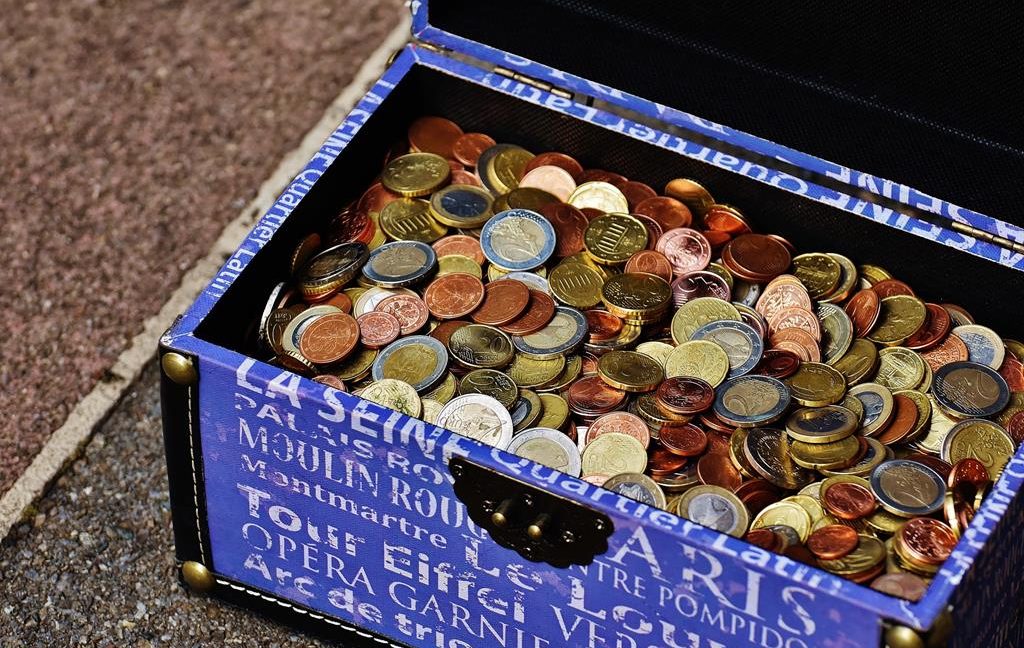 A blue opened box with white writing on it filled up with coins