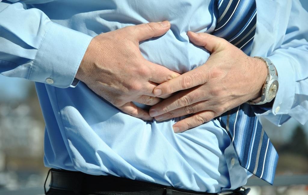 Image of a man holding his stomach in pain