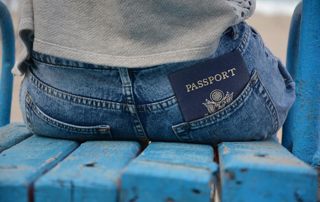 Image of a person sitting down on a bench with their passport in back pocket